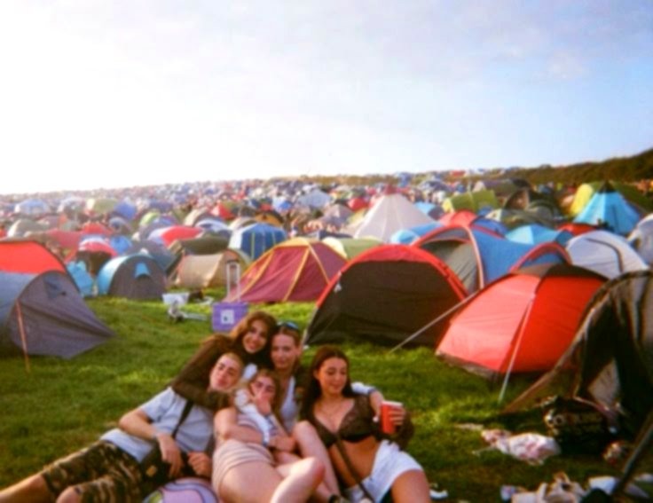 A group of friends in front of their tents at the festival campground